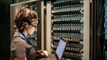 Woman standing with a laptop at datacenter
