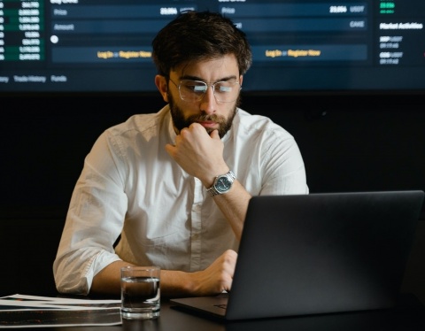 man with beard and glasses working with data on laptop