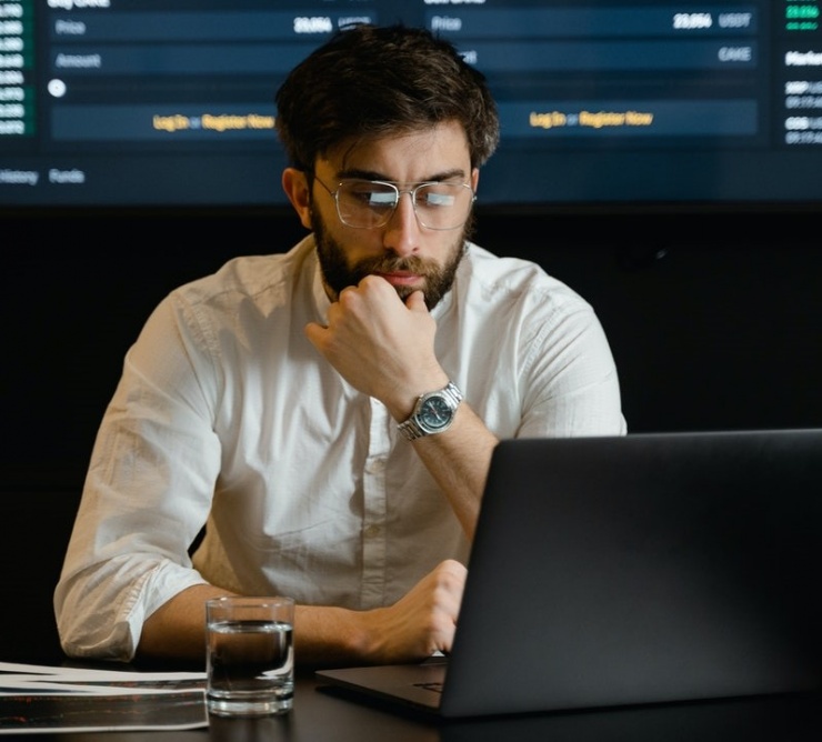man with beard and glasses working with data on laptop